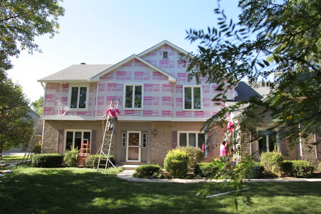 open box roofing working on installing james hardie siding on ladders