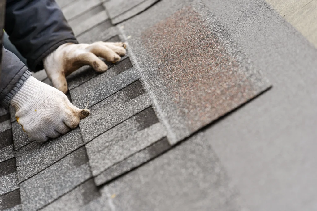Roofing contractor installs asphalt shingle on residential rooftop