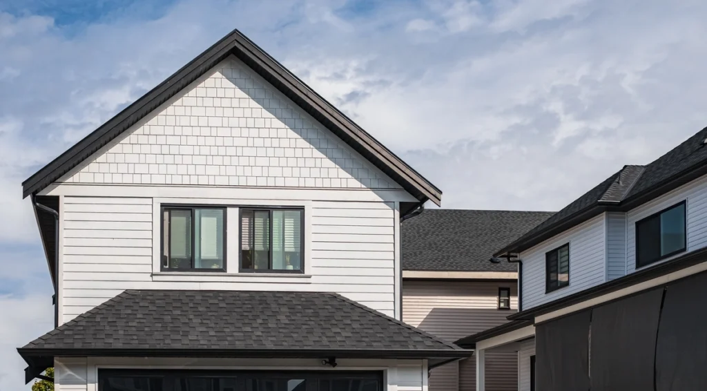 White house with new dark shingle roof installed to increase home value